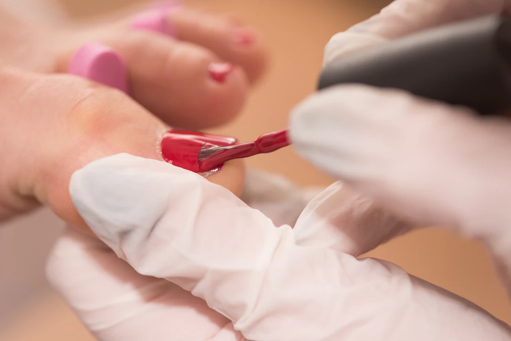 Red polish being applied to toes